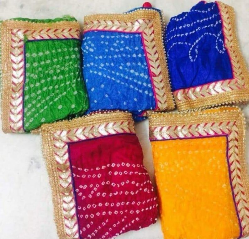 K&ouml;nnte beinhalten: Eine Sammlung farbenfroher, gemusterter Textilien. Die Stoffe sind in Gr&uuml;n-, Blau-, Rot- und Gelbt&ouml;nen gehalten und weisen ein wei&szlig;es Punktmuster auf. Jedes St&uuml;ck hat einen Gold- und Silberrand.