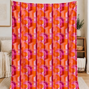 May include: A rectangular throw blanket featuring a repeating geometric pattern of vertical stripes in shades of bright pink, magenta, and orange. The design incorporates overlapping semi-circular shapes that create a rhythmic, layered visual effect.