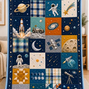 May include: A quilted blanket featuring a space-themed patchwork design with illustrations of astronauts, planets, a rocket ship, a lunar rover, a satellite, a telescope, and stars on a dark blue background with plaid and geometric patterned squares.