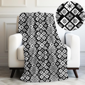 May include: Black and white throw blanket with a geometric pattern of stars and squares.