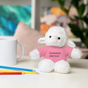 Peut inclure: Un agneau en peluche blanc portant un t-shirt rose avec le texte "Personnaliser votre texte".