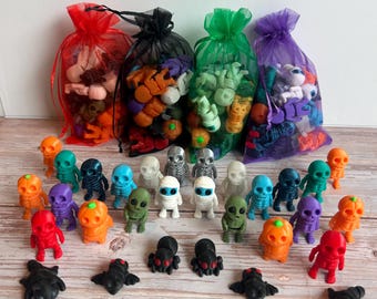 Peut inclure: Une collection de figurines miniatures et de breloques sur le thème d'Halloween. Les figurines comprennent des squelettes, des extraterrestres, des araignées et des citrouilles de différentes couleurs. Les breloques sont dans des sacs en filet rouges, noirs, verts et violets.