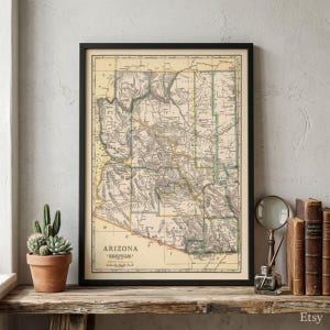 Op de afbeelding: Een ingelijste vintage kaart van Arizona met gedetailleerde provincielijnen, topografische markeringen en geografische labels in zwarte inkt op een crèmekleurige achtergrond, met de titel Arizona onderaan de kaart gedrukt.