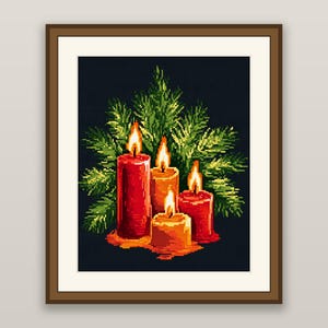 May include: A cross-stitch embroidery pattern framed in brown, depicting four lit candles in shades of red and orange. The candles are arranged in front of green pine branches against a dark background, with visible wax drips at the base.