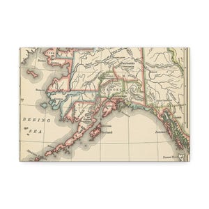 May include: A vintage-style map of Alaska printed on a textured canvas surface. The map features a cream-coloured background with muted pink and green borders highlighting regional boundaries. It displays geographical labels like Bering Sea, Nome, Fairbanks, Anchorage, and Juneau in black serif font.