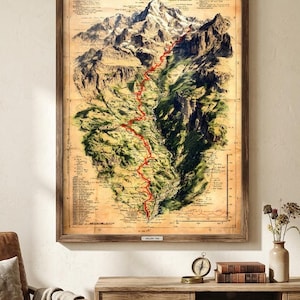 May include: A framed vintage-style topographical map print featuring a detailed mountain range with a prominent red trail line winding through the peaks and valleys. The map includes technical text annotations, grid lines, and a sepia-toned background.