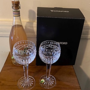 May include: Two Waterford crystal wine glasses with a bottle of sparkling wine and a black box with the Waterford logo.
