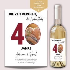 May include: A white wine bottle with a label featuring the text "DIE ZEIT VERGEHT, die Liebe bleibt" and the number 40. A matching card with the same design is next to the bottle. The card and label include a photo of an embracing couple.