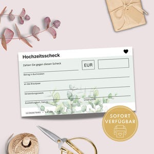 Op de afbeelding: Een witte trouwcheque met de Duitse tekst "Hochzeitsscheck" en een hartpictogram. De cheque heeft lijnen voor het invullen van details en een bloemenontwerp. Een gouden sticker met de tekst "SOFORT VERFÜGBAR" is ook zichtbaar.