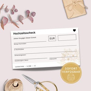 以下が含まれることがあります： ドイツ語の「Hochzeitsscheck」というテキストと詳細を入力するフィールドがある白いウェディングチェック。ハートのシンボルと花の模様が含まれています。「SOFORT VERFÜGBAR」というテキストの金色のステッカーも表示されています。