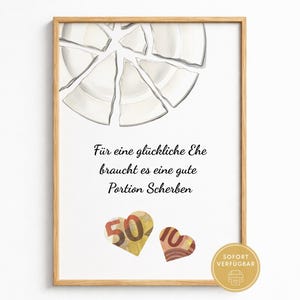 May include: A framed print featuring a white broken plate at the top, the German text "Für eine glückliche Ehe braucht es eine gute Portion Scherben" in the centre, and two heart-shaped cutouts made from fifty and ten euro banknotes below.