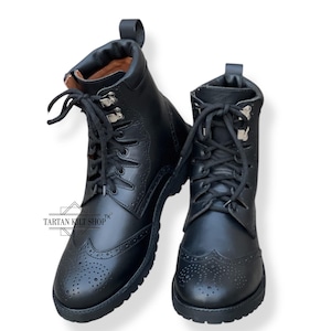 Könnte beinhalten: Ein Paar schwarze Schnürstiefel aus Leder mit Brogue-Muster und einem Tartan Kilt Shop-Logo an der Seite.
