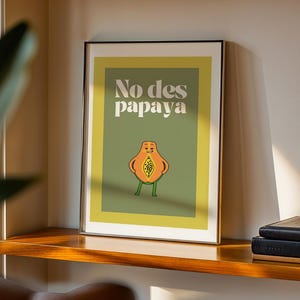 May include: A framed print with a green background and a yellow border. The print features a cartoon papaya with legs and arms, and the text "No des papaya".