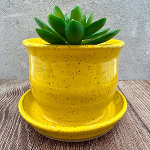 May include: A set of three ceramic mugs with a speckled, matte finish. The mugs are in shades of cream, light gray, and dark gray. Each mug has a simple, minimalist design, perfect for coffee or tea.