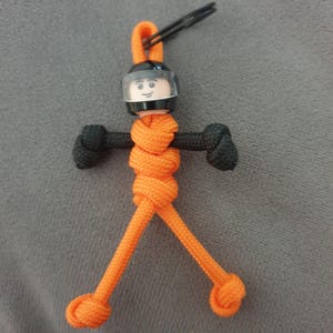 Orange och svart mini-motorcyklistfigur nyckelring.