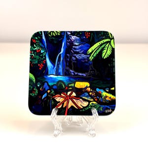 Może przedstawiać: Kwadratowy, dekoracyjny szklany talerz przedstawiający scenę wodospadu z zielonymi liśćmi, niebieską wodą i czerwonymi jagodami. Talerz jest podparty przezroczystym plastikowym stojakiem.