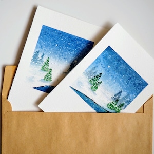 Set van 2 handgeschilderde aquarel kerstkaarten, winterwonderland besneeuwd landschap met groenblijvende bomen - unieke kerstkaart