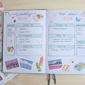 Pode incluir: Um planejador semanal com um esquema de cores azul claro e verde. O planejador tem uma lista de tarefas pendentes e uma se&ccedil;&atilde;o para notas. O planejador &eacute; decorado com adesivos de flores, borboletas e comida. O planejador est&aacute; aberto para a semana do 10, com os dias da semana listados no topo de cada p&aacute;gina. O planejador est&aacute; sobre uma superf&iacute;cie de madeira.