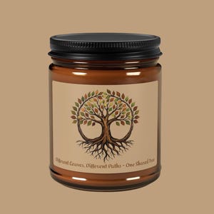 Può includere: Un barattolo di vetro marrone con coperchio nero. L'etichetta presenta un disegno ad albero con foglie colorate e la scritta "Different Leaves, Different Paths - One Shared Tree". Il barattolo è riempito con una sostanza di colore chiaro.