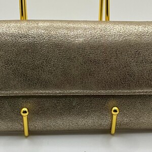 May include: A gold-coloured leather wallet with a silver-coloured logo that says "juicy" with a small rhinestone on the end.