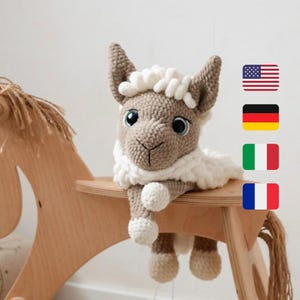 May include: A crocheted llama toy with a white fluffy mane and brown fur, sitting on a wooden rocking horse. The llama has large brown eyes and a small brown nose.