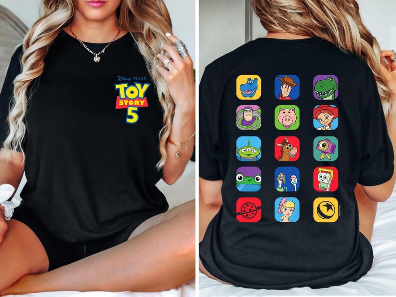 May include: A black t-shirt featuring a small Disney Pixar Toy Story 5 logo on the front left chest. The back of the shirt displays a grid of fifteen colorful square icons depicting various characters and symbols from the Toy Story film franchise.