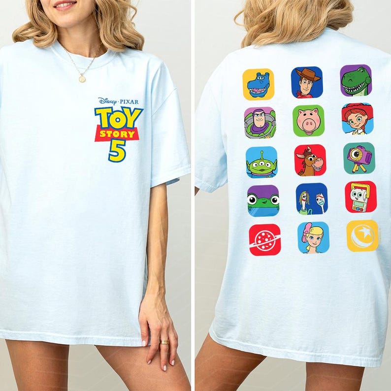 May include: A light blue t-shirt featuring the Disney Pixar Toy Story 5 logo on the front chest. The back displays a grid of fifteen colorful square icons depicting various characters and symbols from the Toy Story film franchise.