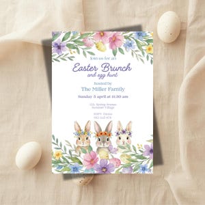 Puede incluir: Invitación a un brunch de Pascua y búsqueda de huevos con ilustraciones de acuarela de conejitos, flores y huevos. La invitación incluye el texto "Join us for an Easter Brunch and egg hunt" y detalles del evento, incluyendo fecha, hora e información de RSVP.