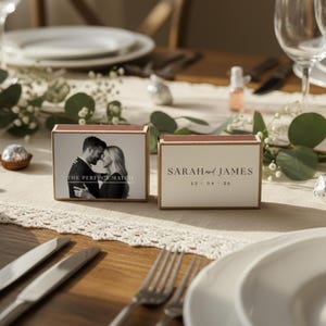 Peut inclure: Deux boîtes d'allumettes rectangulaires sur le thème du mariage. L'une présente une photo en noir et blanc d'un couple avec le texte "THE PERFECT MATCH". L'autre affiche les noms "SARAH and JAMES" et la date "15 - 04 - 26."