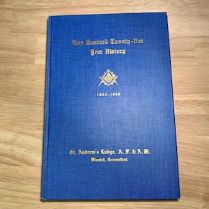 May include: A blue book titled "One Hundred Twenty-five Year History" with gold lettering and a Masonic emblem. The book's cover also includes the text "St. Andrew's Lodge. A. F. & A. M. Winsted, Connecticut" and the years 1823-1848.