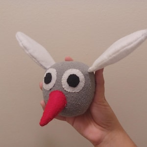 May include: A gray plush toy with white ears and a red nose. The toy has large black eyes and a round body.