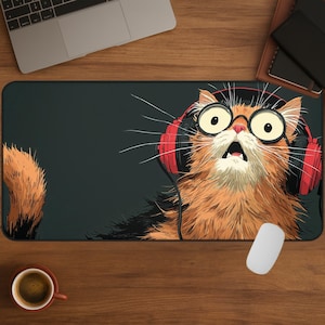 Puede incluir: Alfombrilla de ratón rectangular con un gato de dibujos animados con pelaje naranja, que lleva auriculares rojos y gafas redondas. El gato tiene una expresión de sorpresa. Un ratón blanco está en el lado derecho de la alfombrilla.