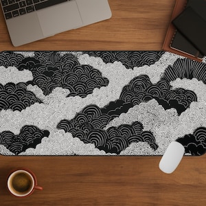 May include: Black and white patterned desk mat featuring a cloud-like design. The mat has a repeating pattern of swirling shapes in black and white. A computer mouse and a coffee cup are visible on the wooden desk.