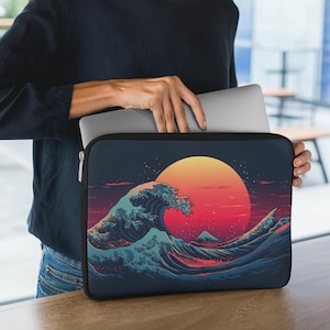May include: A black laptop sleeve featuring a colourful graphic of a large wave crashing against a red and orange sunset. The wave is blue, green and white. The sleeve has a zipper on the side.
