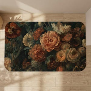 May include: A rectangular floral rug featuring a dark background with a variety of flowers in shades of orange, peach, cream, and dark red. The rug has rounded corners and is placed on a light wood floor.