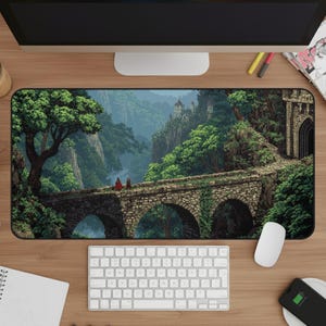 May include: A rectangular mouse pad featuring a pixelated landscape with a stone bridge, lush green trees, and a castle in the distance. Two figures in red cloaks stand on the bridge. The pad is on a wooden desk with a keyboard and mouse.