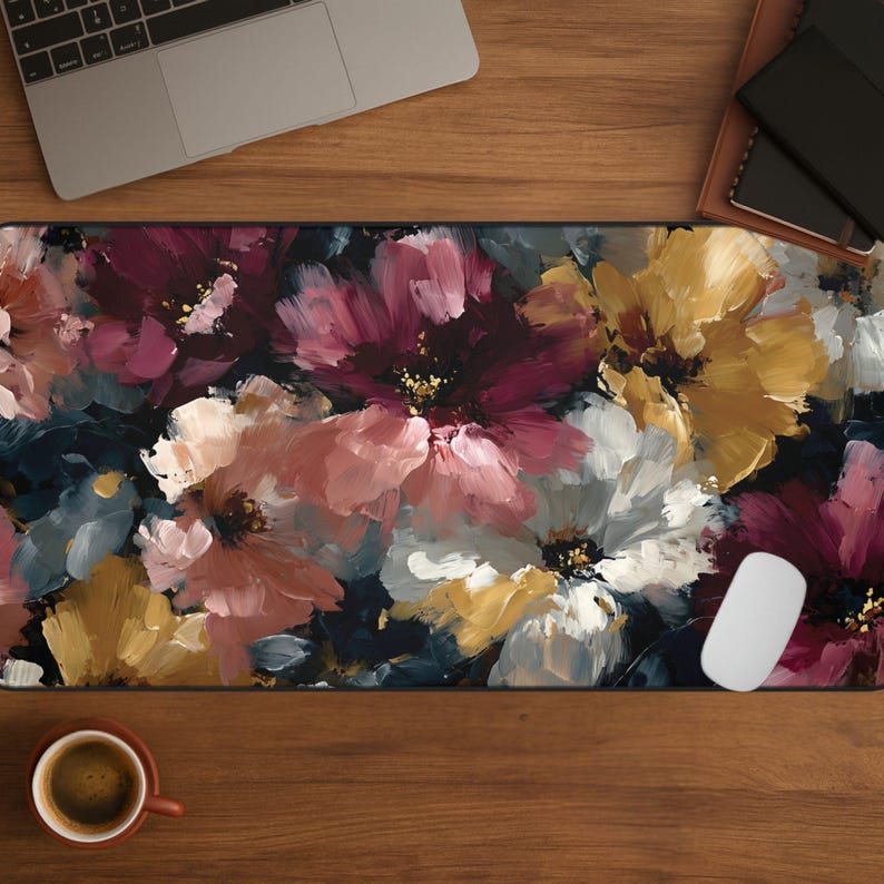 May include: A floral mousepad featuring a vibrant, painterly design of large flowers in shades of pink, white, yellow, and burgundy against a dark background. A white computer mouse is on the right side of the mousepad. A laptop and a cup of coffee are also visible.