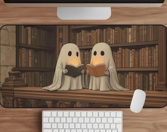 Puede incluir: Alfombrilla de ratón rectangular con dos fantasmas de dibujos animados leyendo libros en una biblioteca. Los fantasmas están envueltos en sábanas blancas, con ojos brillantes y libros abiertos. El fondo muestra una estantería detallada.
