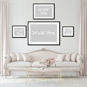 May include: A living room scene featuring framed prints of various sizes: 8x10 inches, 11x14 inches, 16x24 inches, and 24x36 inches. The prints are displayed above a cream-colored sofa with decorative pillows. The room has light-colored curtains and a patterned rug.