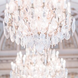 Puede incluir: Una gran l&aacute;mpara de ara&ntilde;a de cristal adornada con muchos brazos y cristales colgantes. La l&aacute;mpara est&aacute; encendida y la luz se refleja en los cristales, creando un efecto brillante.