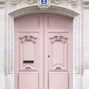 May include: A pink double door with ornate details and a brass doormat. The door is numbered "2" in blue.