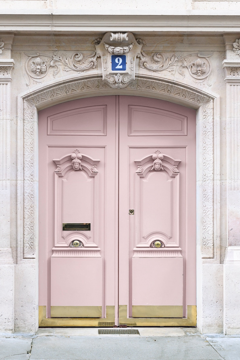May include: A pink double door with ornate details and a brass doormat. The door is numbered "2" in blue.