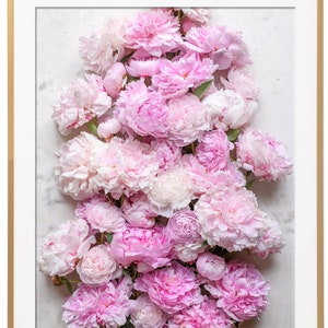 May include: A close-up of a bouquet of pink peonies arranged on a white marble background. The peonies are in full bloom and have a soft, delicate texture.