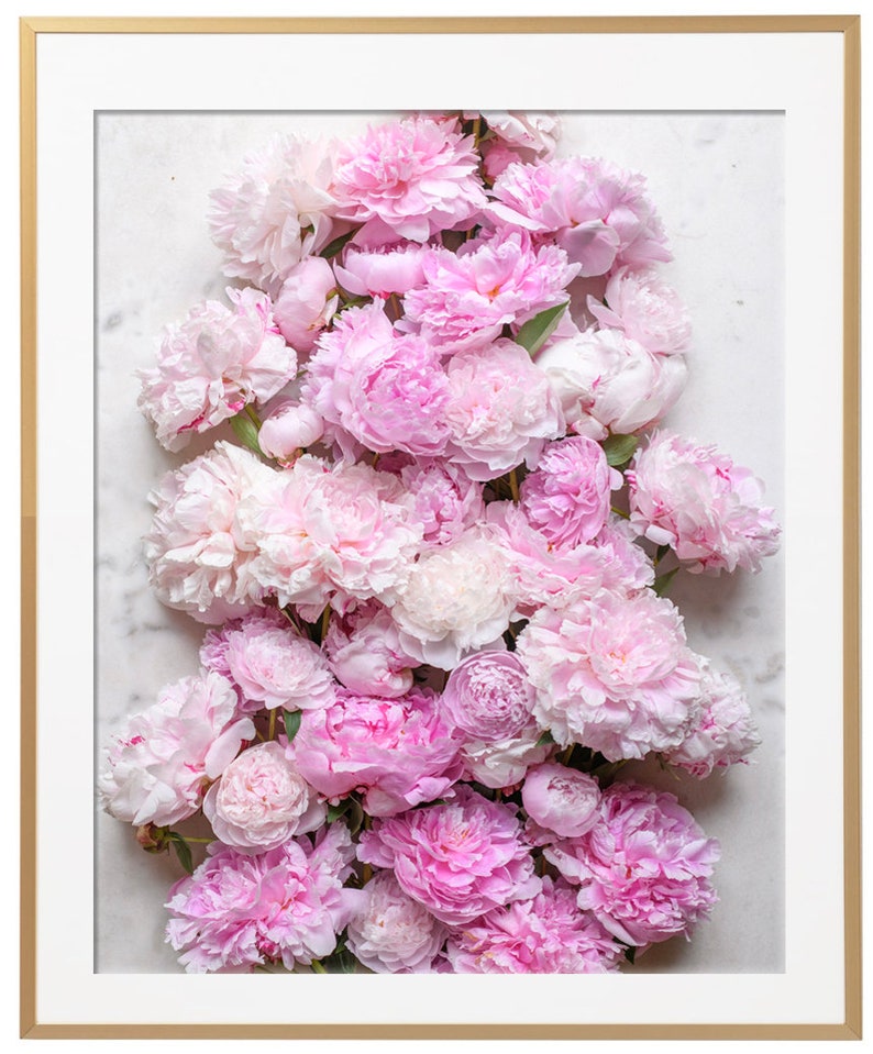 May include: A close-up of a bouquet of pink peonies arranged on a white marble background. The peonies are in full bloom and have a soft, delicate texture.