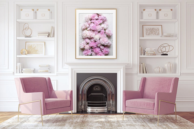 May include: A framed print of a cluster of pink peonies arranged in a vertical stack. The peonies are in various shades of pink, from light to dark. The print is hanging on a white wall above a fireplace.