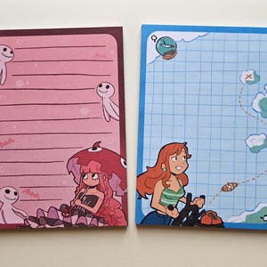 Peut inclure: Deux blocs-notes illustrés. L'un est rose avec une fille de dessin animé et des personnages blancs souriants. L'autre est bleu avec une carte et une fille de dessin animé conduisant un bateau. Les deux ont des pages lignées.