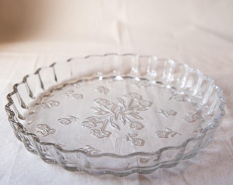 May include: A clear glass pie plate with a scalloped edge and a floral design.