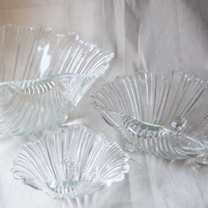 May include: Three clear glass bowls with a fluted design. The bowls are nested together, with the largest bowl at the bottom and the smallest bowl at the top.