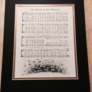 May include: A vintage sheet music page titled "The Church In The Wildwood". The sheet music includes the lyrics and musical notation for the song. The page is decorated with a black and white illustration of a cluster of flowers.