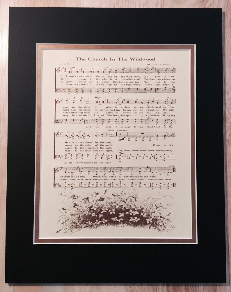 May include: A vintage sheet music print of the song "The Church In The Wildwood". The sheet music is printed in brown ink on cream-coloured paper. The lyrics and musical notes are visible. The image also includes a small illustration of a cluster of flowers at the bottom of the page.